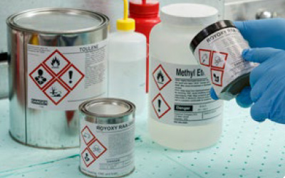 Chemik aplikuje na nádobku etiketu GHS.