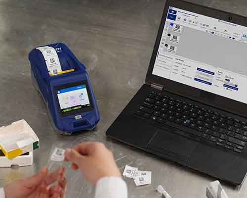 Osoba aplikující etiketu vytištěnou na tiskárně M611 na laboratorní sklíčko.